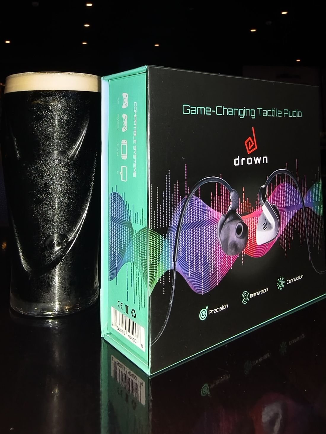 The original box beside a pint of stout on a dark bar